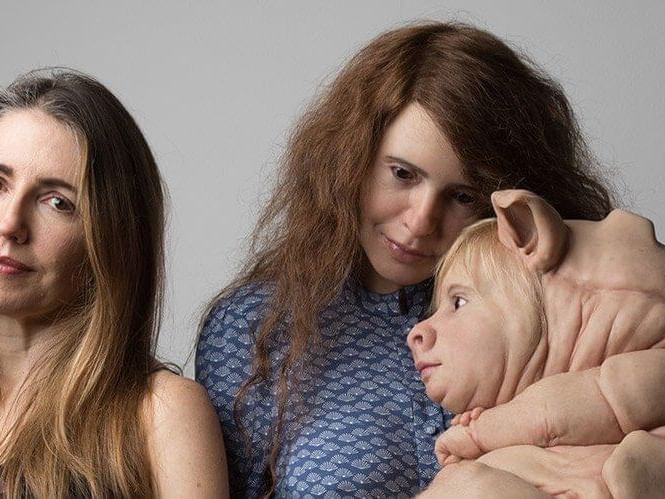 Hyper-realistic sculpture of two women with an infant figure featuring pig-like features art display at The Sebel Brisbane