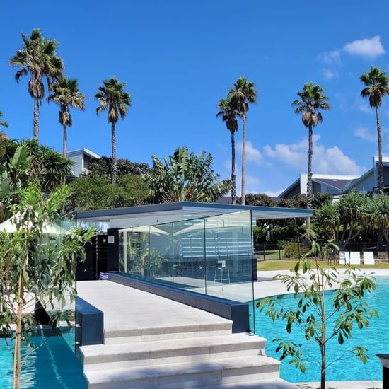 outdoor pool with glass bridge across surrounded by palm trees