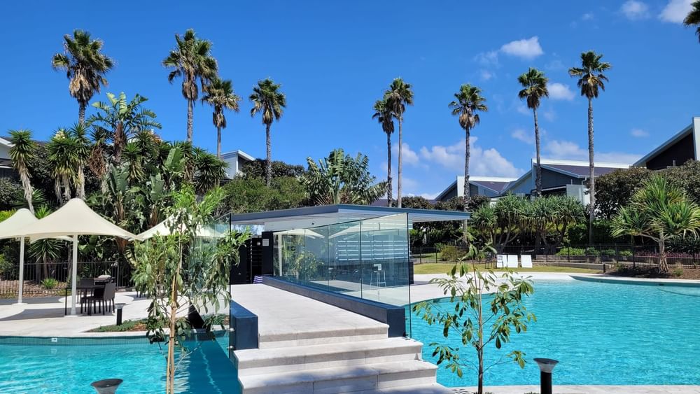 outdoor pool with glass bridge across surrounded by palm trees
