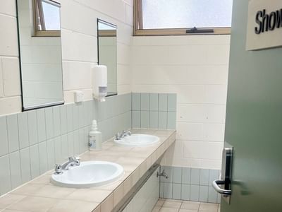 Two sinks with faucets and soap dispenser in a tiled washroom with 