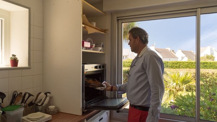 A man putting food into the oven at Hotel Armen Le Triton
