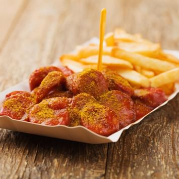 Nahaufnahmefoto von Currywurst, die auf einem Tisch in der Nähe von Titanic Hotels in Berlin serviert wird