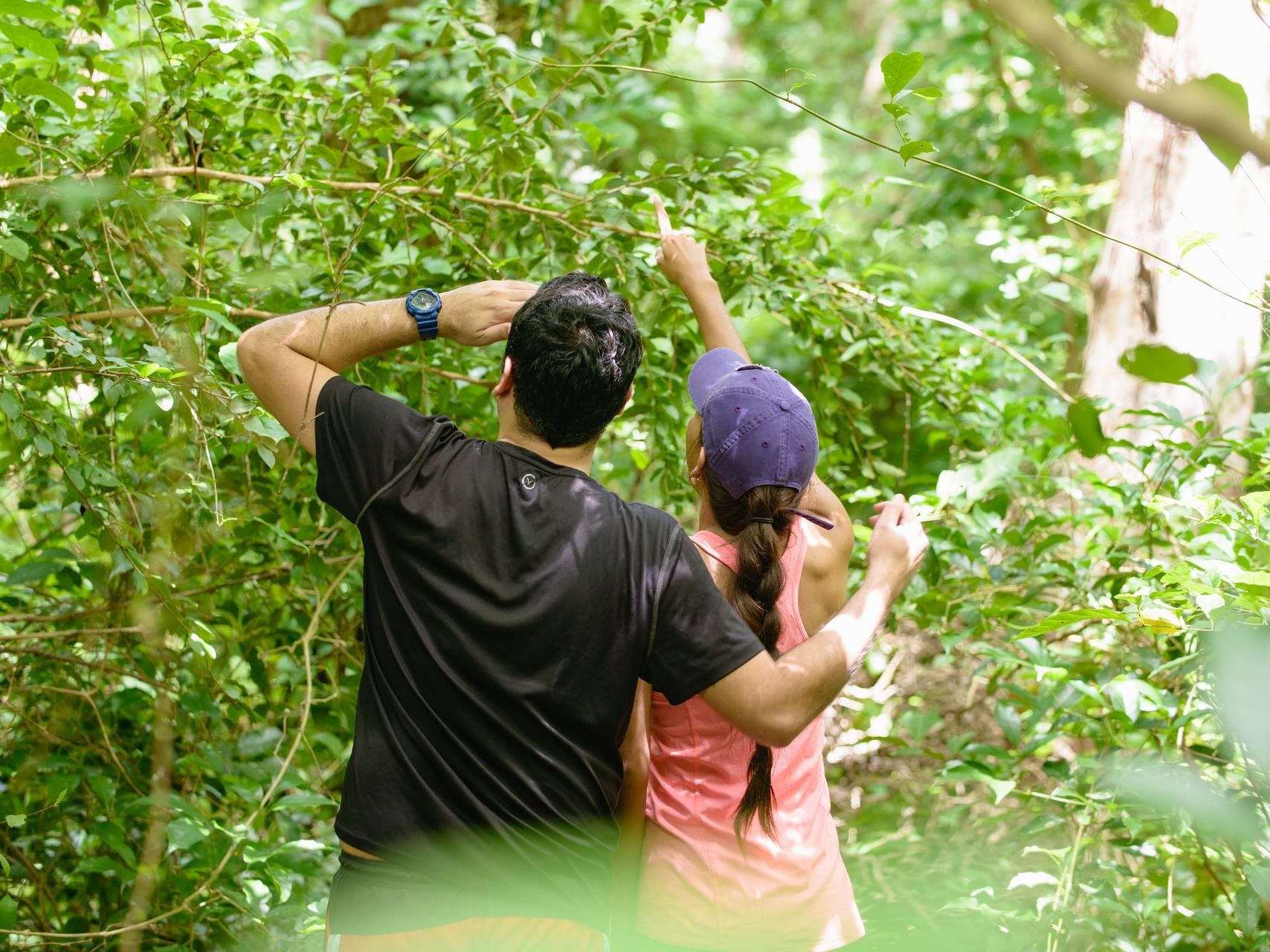 Couple hiking under lush green trees by a dense forest trail, Nicaragua experience near Morgan's Rock Reserve & Ecolodge