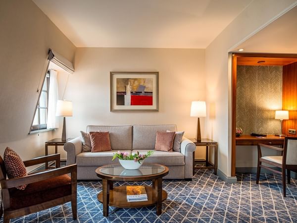 Elegant lounge area with sofa, coffee table, and wooden chairs at Warwick Grand-Place Brussels.