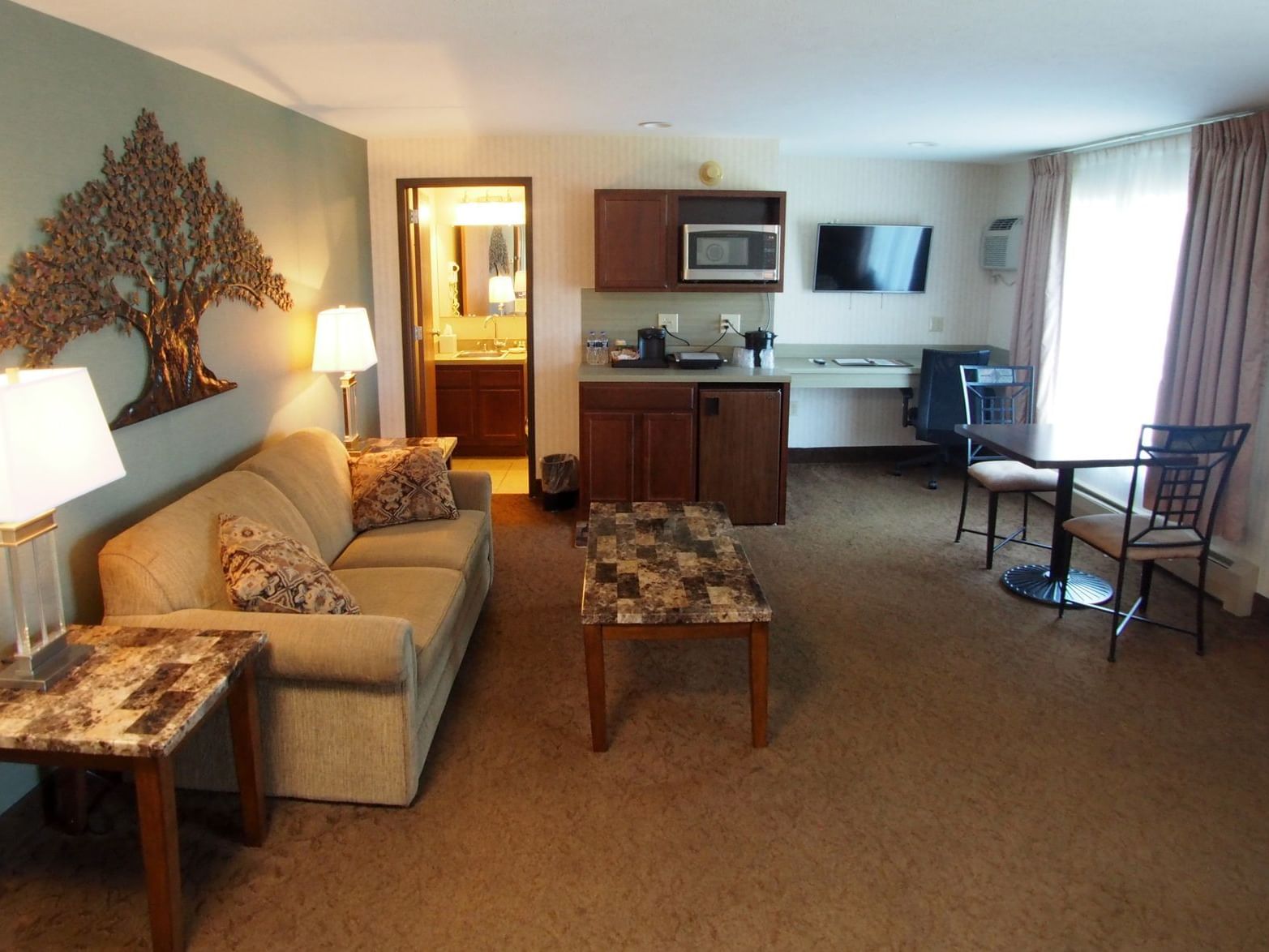 Living area with couch and dining area in a Deluxe Suite at Evergreen Resort in Cadillac.