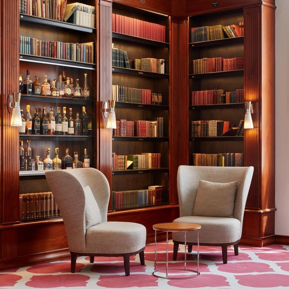 Elegante Bibliothek mit Holzregalen, gepolsterten Stühlen und Büchern.