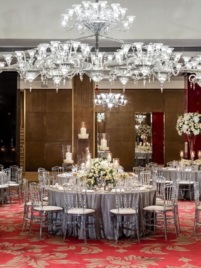 Wedding reception featuring elegant round tables with floral centerpieces under sparkling chandeliers at The May Fair Hotel