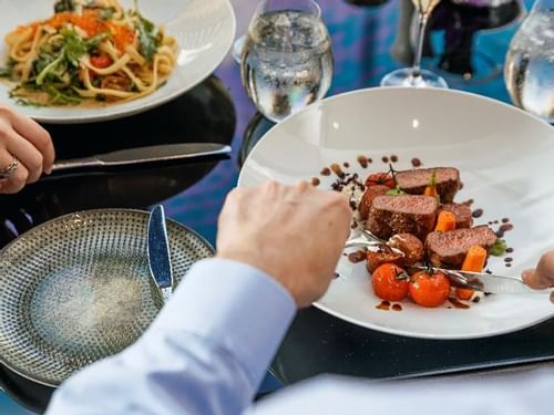 Diners with plates of pasta and steak at Restaurant Bistro Suzette in Sofitel Brisbane Central