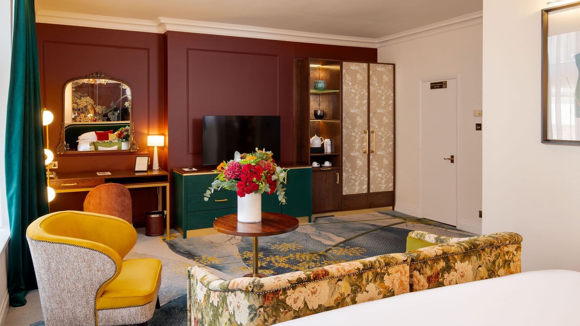 Elegant room with floral couch, yellow chair, TV, and vibrant floral arrangement in the heart of Knightsbridge.