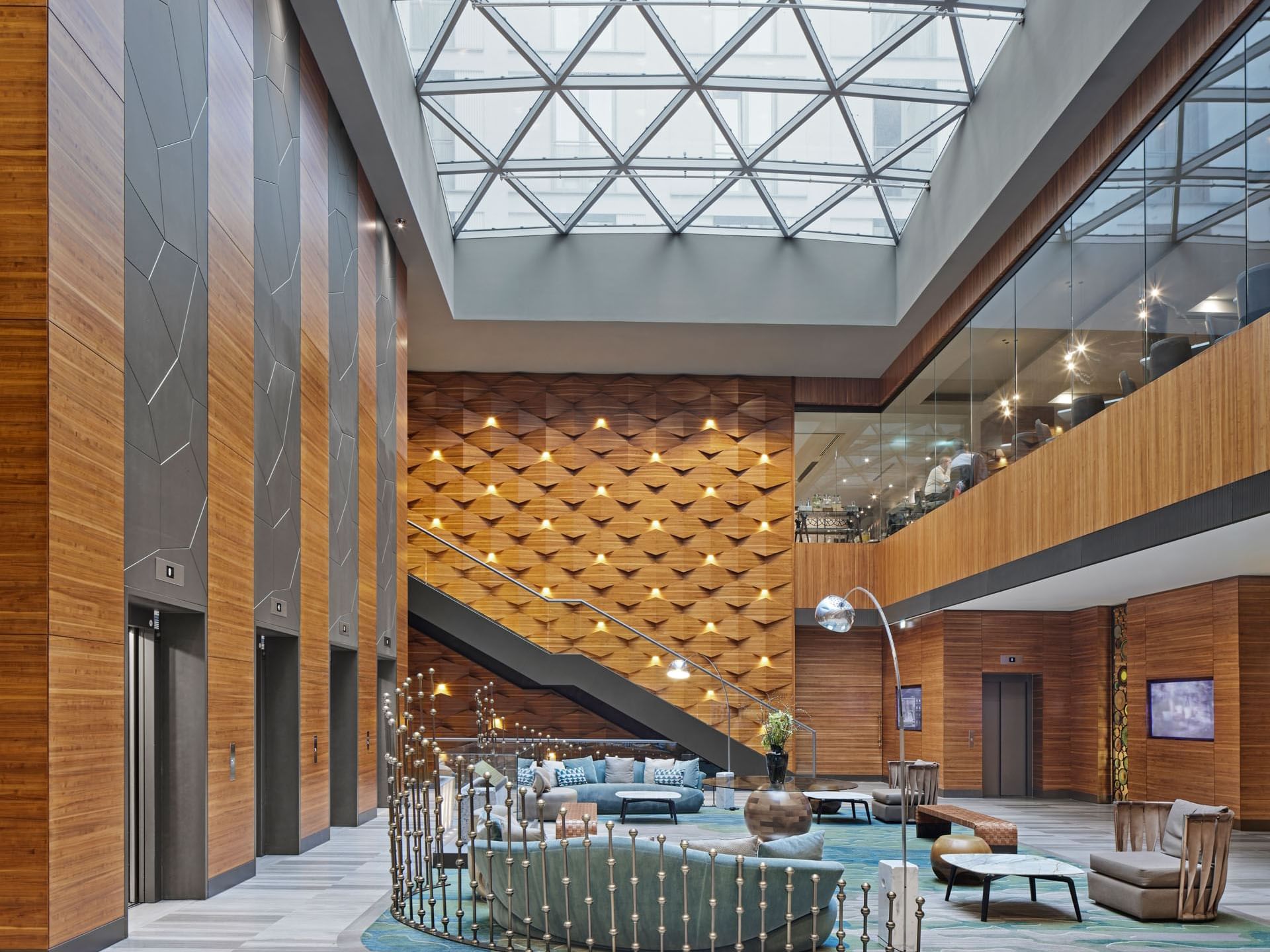 Luxuriöse Lobby im Titanic Chaussee Berlin mit modernem Design, Glasdach, Holzakzenten und stilvollem Lounge-Bereich.