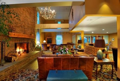 A rustic and cozy hotel lobby with a large brick fireplace and leather seating at The Pointe at Castle Hill