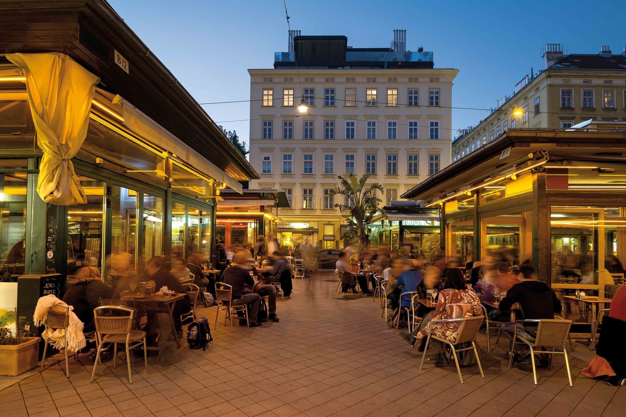Naschmarkt in Vienna at dusk with illuminated restaurants, outdoor seating and visitors