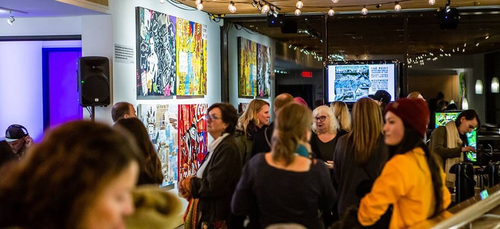Art lovers gather inside a Whistler gallery for a cultural event showcasing bold, expressive paintings.