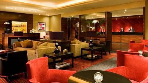 Hall d'entrée élégant avec un coin salon, des touches de bois foncé et un éclairage chaleureux au Warwick Paris Champs-Élysées