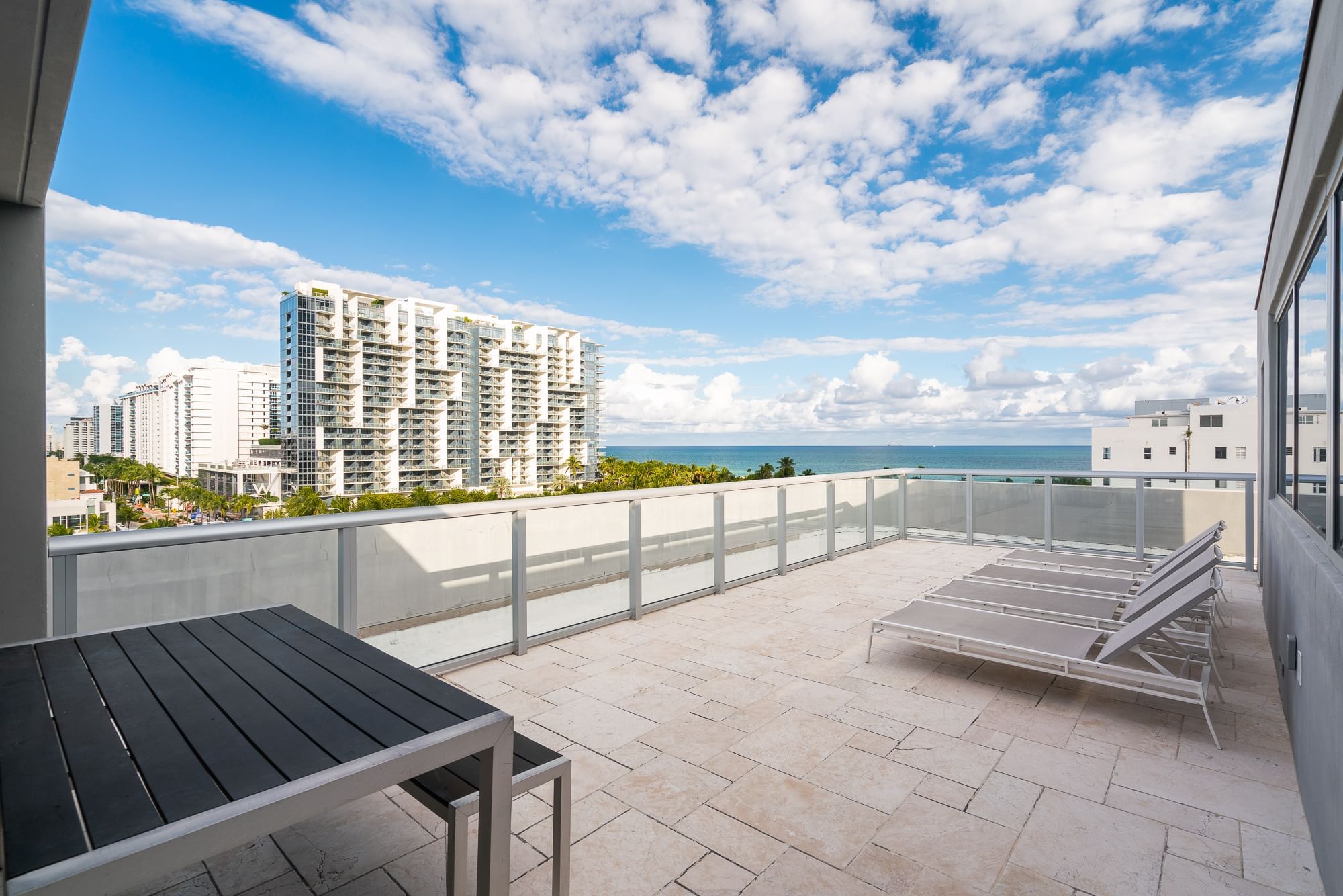 A balcony with a table and chairs overlooking the ocean