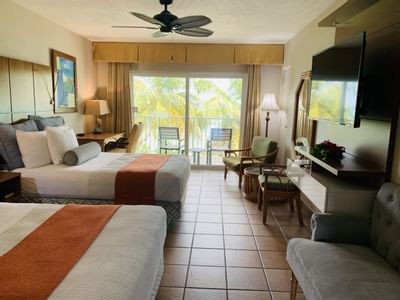 Beds facing wall-mounted TV & armchairs with balcony view in Beachfront Premium Double Bedroom at the Emerald Beach Resort