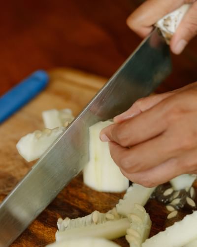 Close-up of fresh fruit being sliced on a wooden board during a meal at Morgan’s Rock Reserve & Ecolodge