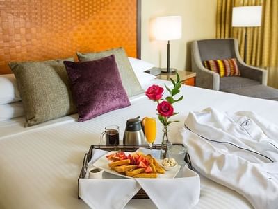 A luxurious breakfast tray with waffles and a carafe on the bed in Urban Premium King at The Paramount Hotel Seattle