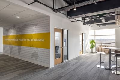 Office space with tables and chairs, a world map on the wall, and large windows at Aramark Ross.