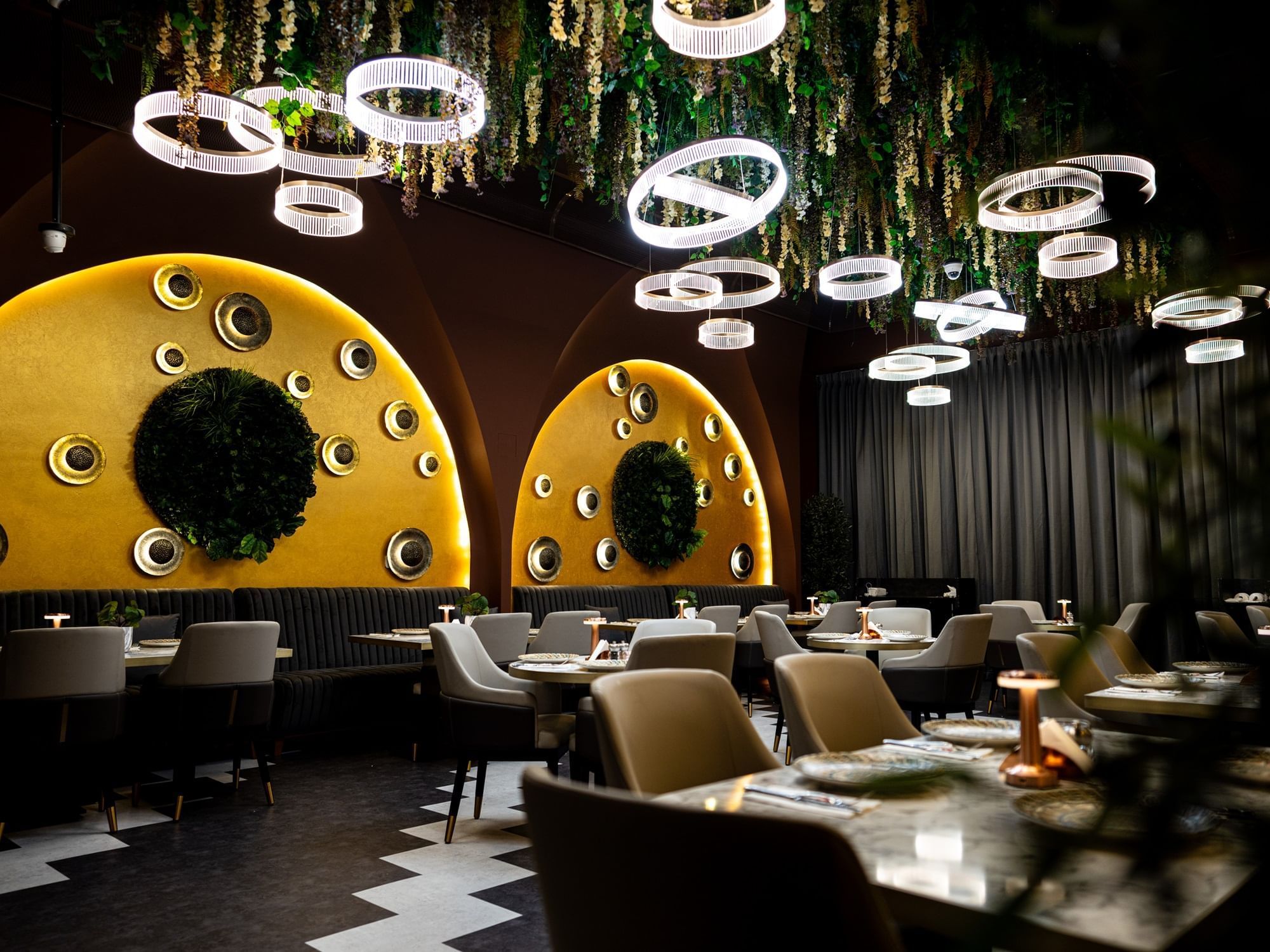 Fine dining Restaurant and Lounge with artistic wall decor, greenery ceiling, and warm lighting at DAMAC Maison Aykon City