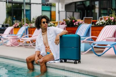 Man with a suitcase posing by outdoor pool edge at The Verb Hotel