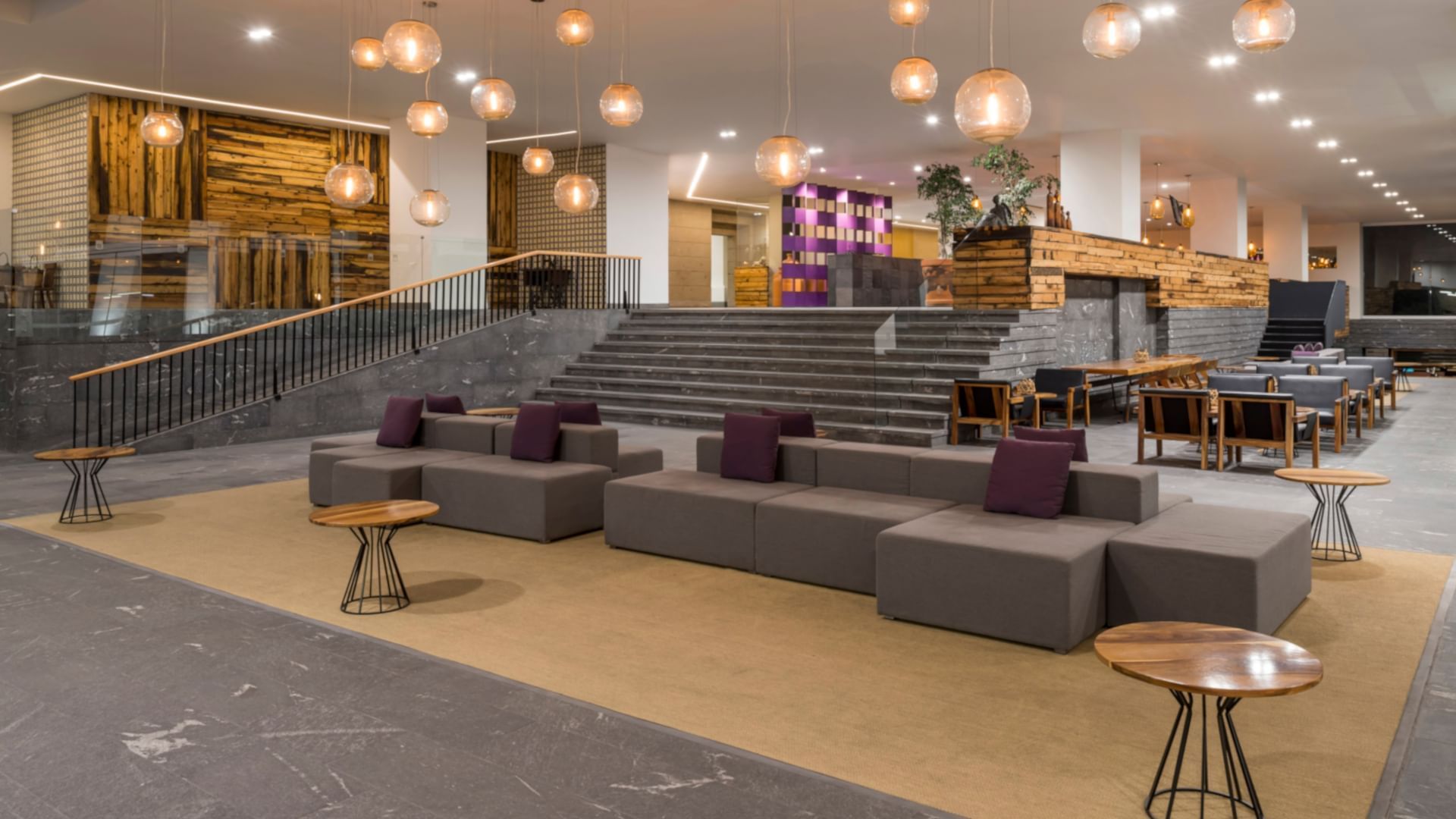 Large lobby with stone stairs, purple accents, and hanging glass globes at Camino Real Puebla Angelópolis