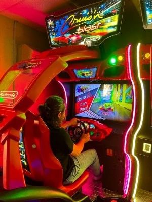 A guest playing a racing game in the video arcade room at Rosen Inn at Pointe Orlando.