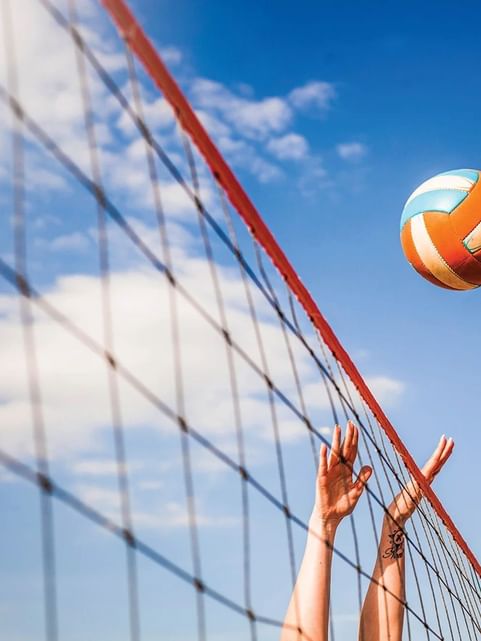 Close-up of hands reaching out to the volleyball in an outdoor court at Cove Pocono Resorts