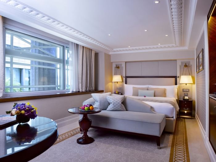 Bed and lounger in Heritage Room with carpeted floors at The Fullerton Hotel Singapore