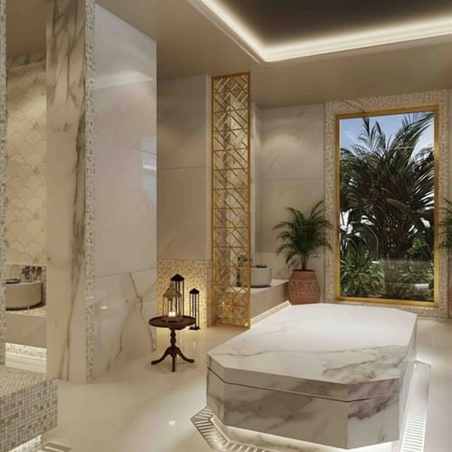 Spa room with marble treatment bed by potted palms under soft lighting at Palmeraie Golf Palace by Pickalbatros
