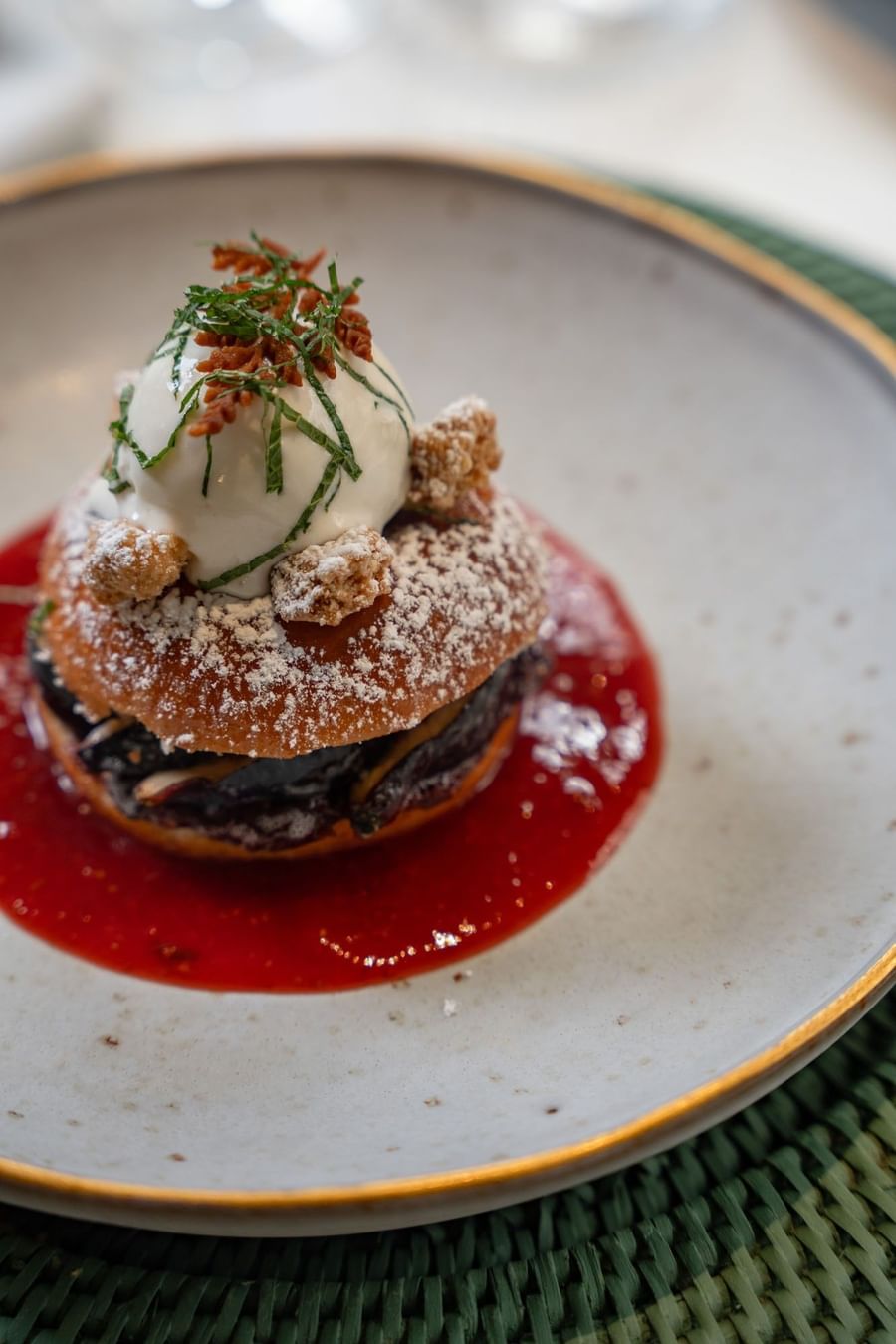 Sweet dessert with white cream and red sauce on a plate, placed by a dark table at Hotel Westminster Paris