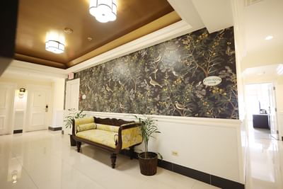 A hallway with floral wallpaper and a bench in the Presidential Suite at Courtleigh Hotel & Suites
