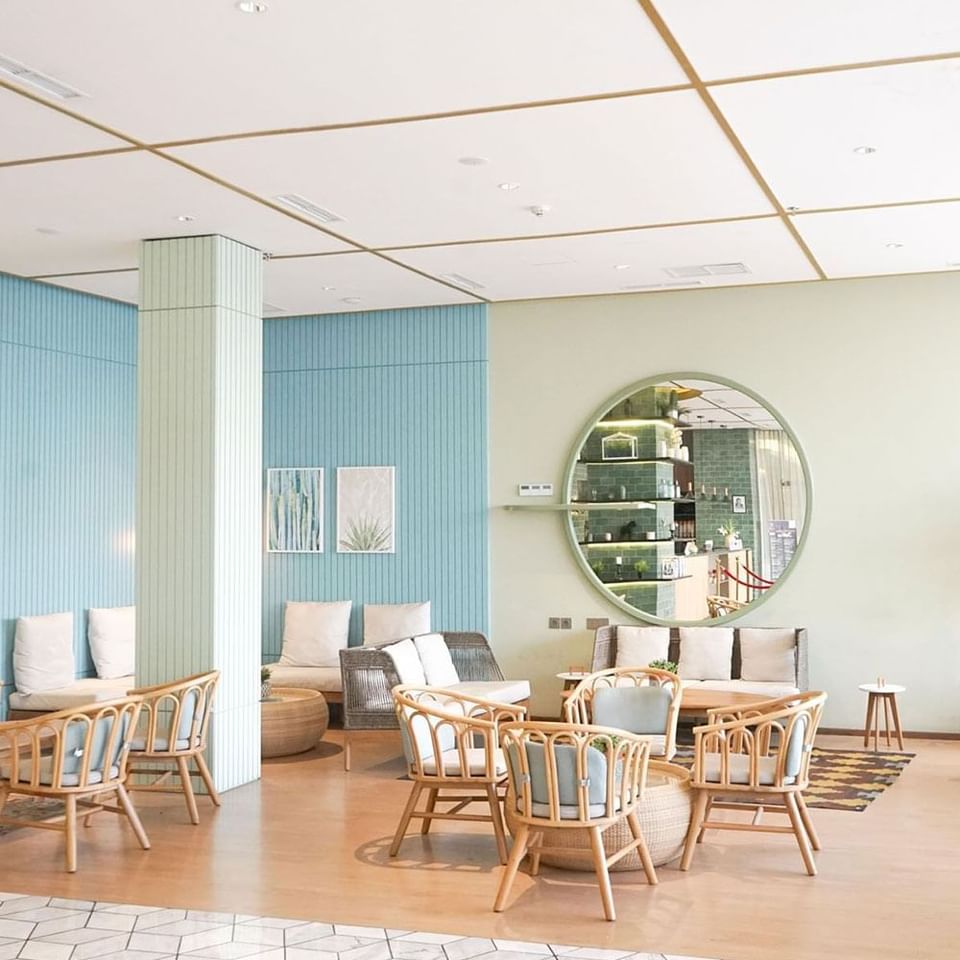 A lobby with a large round mirror and a green wall at LK Pemuda Semarang Hotel & Residences