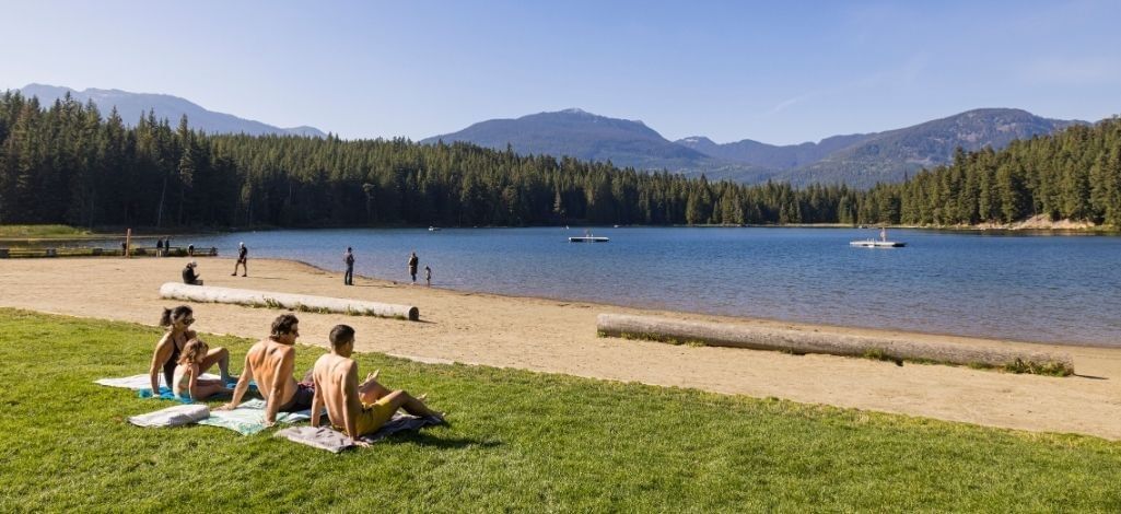 Visitors relaxing on the beach at a lake in Whistler