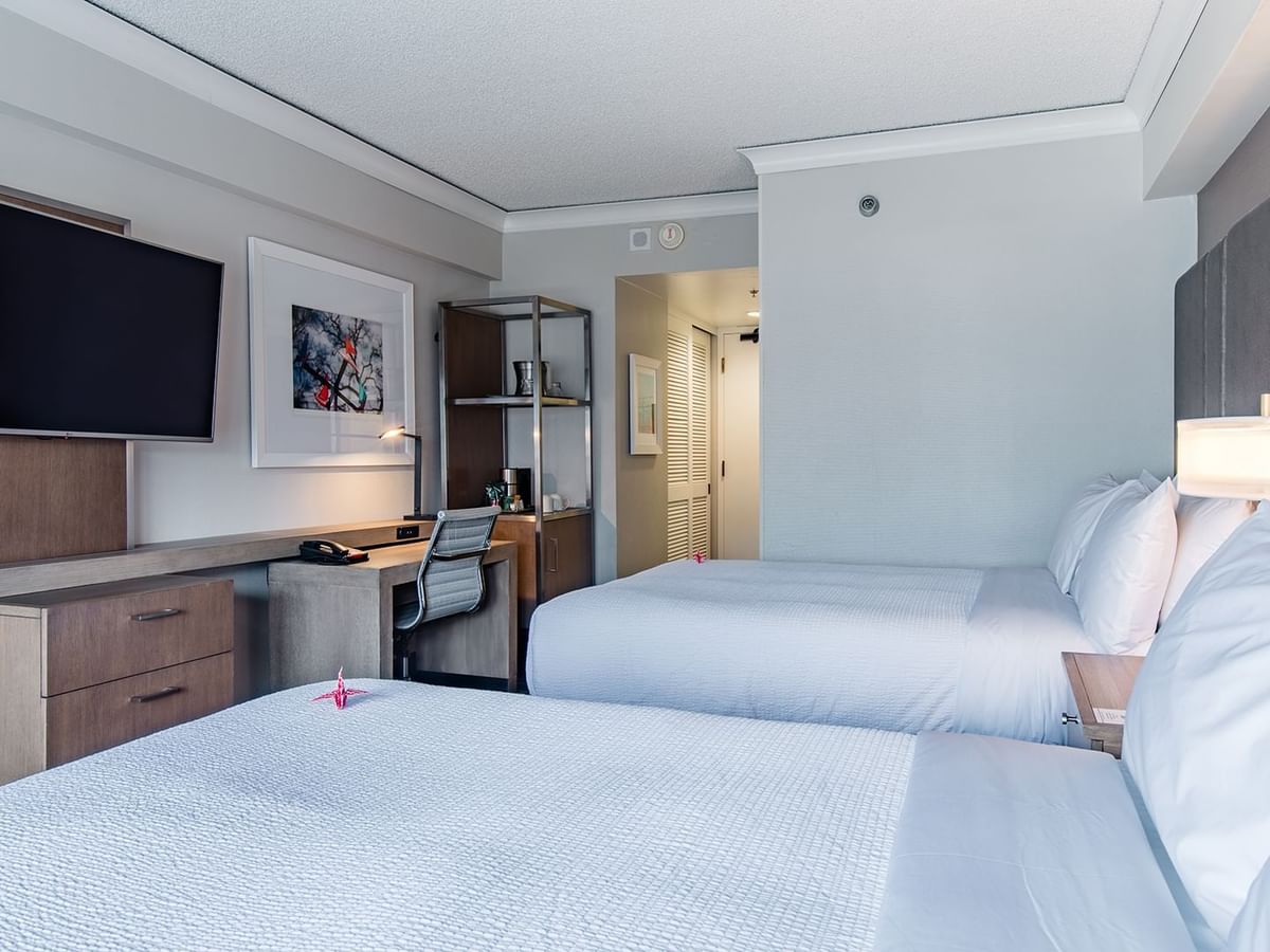 Hotel guestroom with two beds, TV, and desk