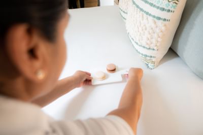 Woman placing board with macarons on a bed at Villa Premiere Boutique Hotel & Romantic Getaway
