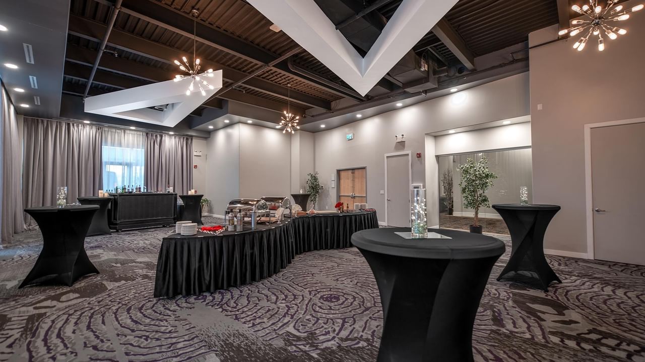 Elegantly arranged tables with black tablecloths and chandeliers.