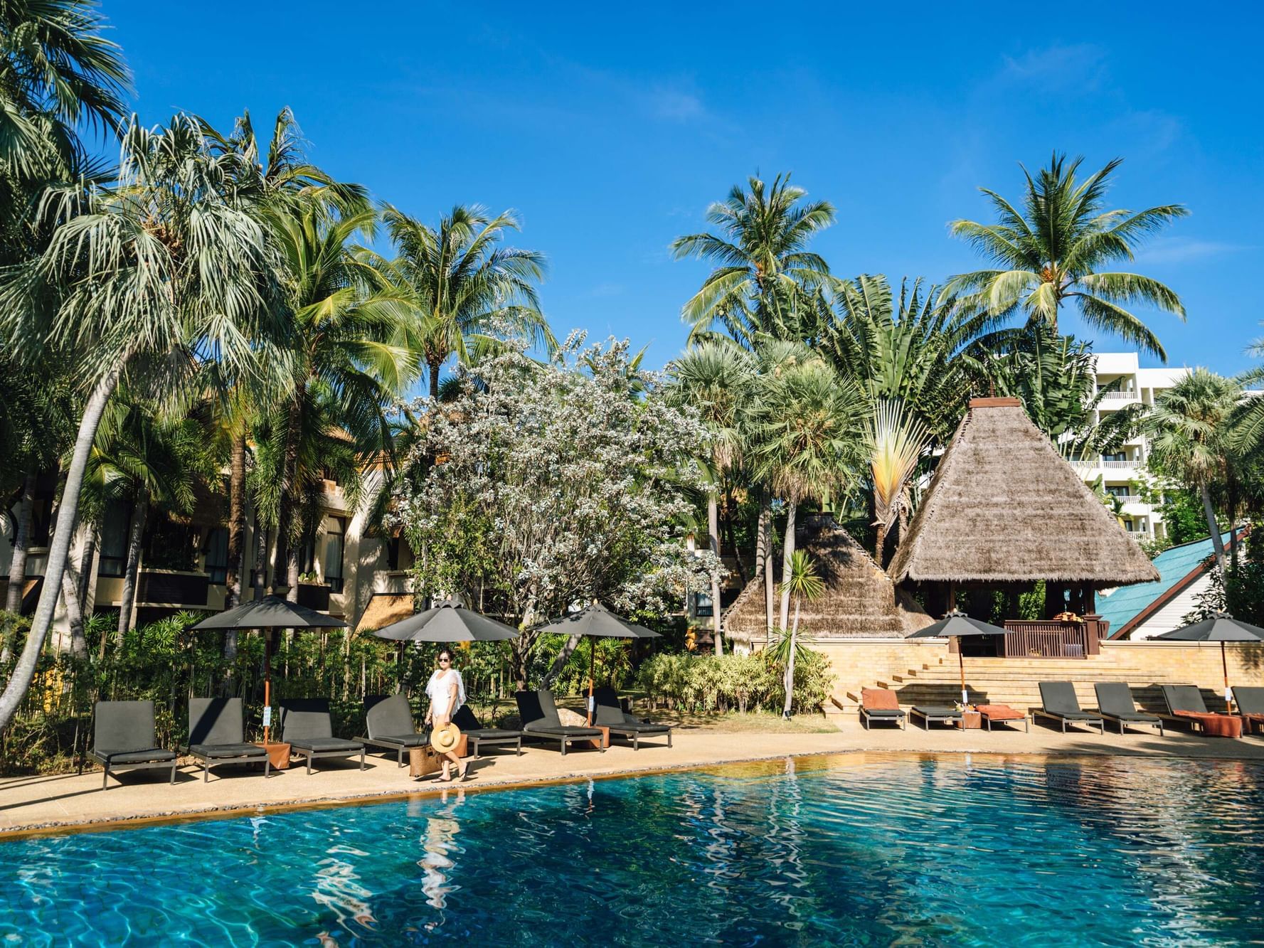 A woman is standing near the Coconut Glove Pool, Surrounded by the Coconut Trees