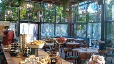 Buffet de nourriture variée sur une table longue avec chaises et plantes suspendues au plafond.
