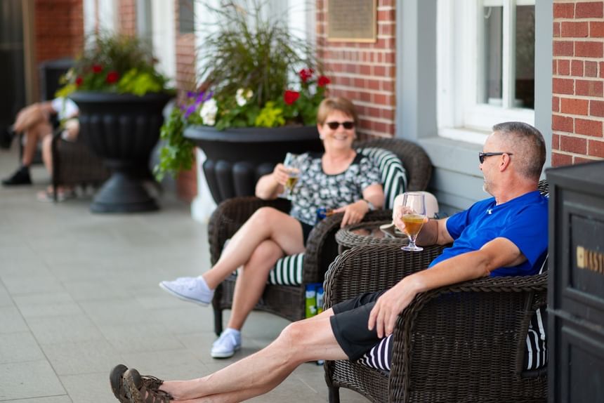 Guests sitting in woven chairs by large planters at Rodd Charlottetown Hotel, a premier rodd Charlottetown