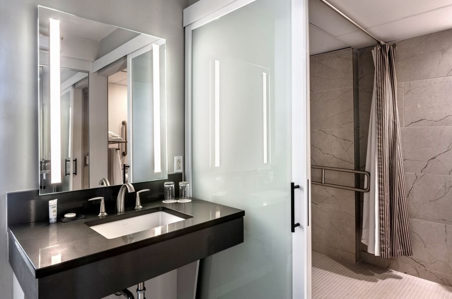 Black marble vanity featuring a square sink by a frosted glass door in Accessible Executive Room at Warwick Seattle