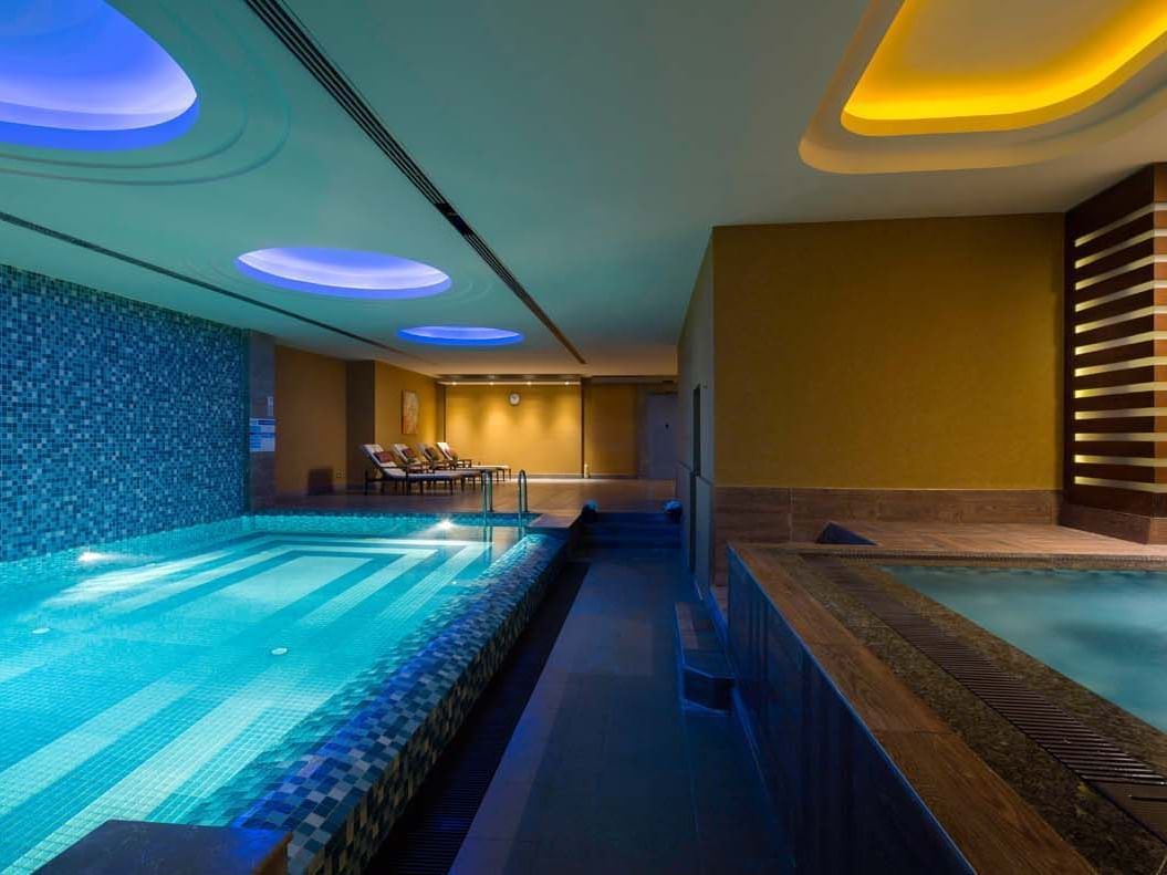 Indoor pool area with lounges at Titanic City Taksim