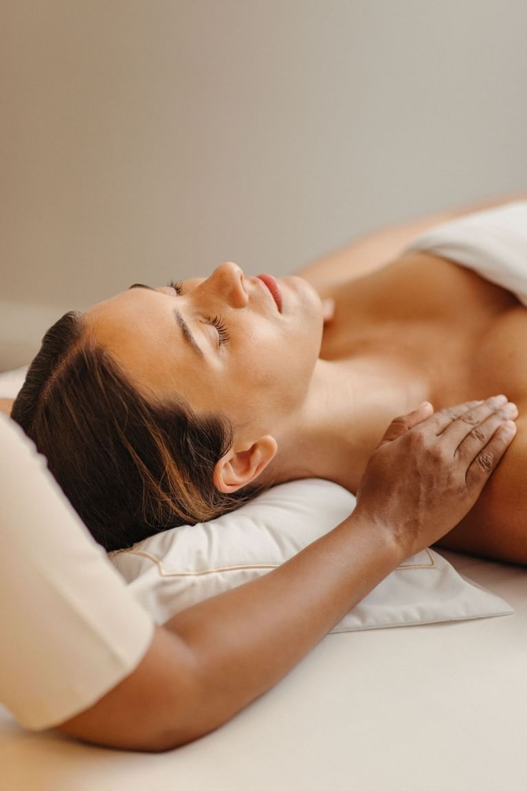 Woman resting during relaxing facial and chest massage treatment inside luxurious spa at Hotel X Toronto wellness