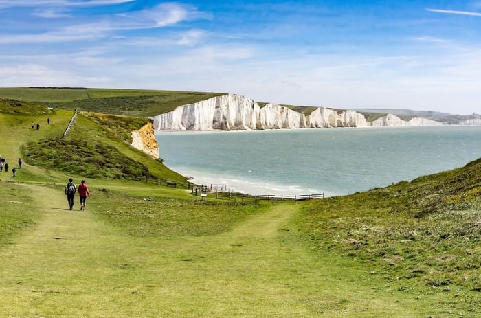 Hikers on coastal path with sea view and chalk cliffs at Seven Sisters Eastbourne