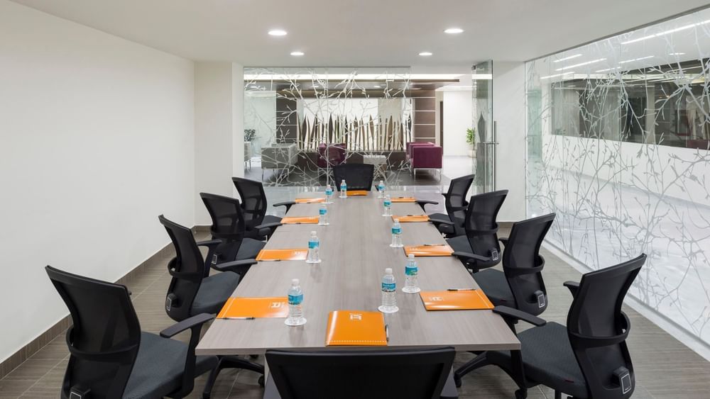 Detroit boardroom with a long wooden table, ergonomic chairs, and frosted glass walls at Real Inn Celaya