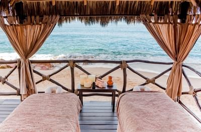 Zona de masajes en el Sunset Plaza Beach Resort, dentro del mejor spa en Puerto Vallarta, con dos camillas, velas y olas de fondo