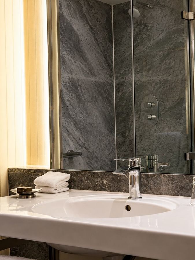 Classic Townhouse King / Twin bathroom with modern sink, mirror, and towels at The Capital Hotel London.