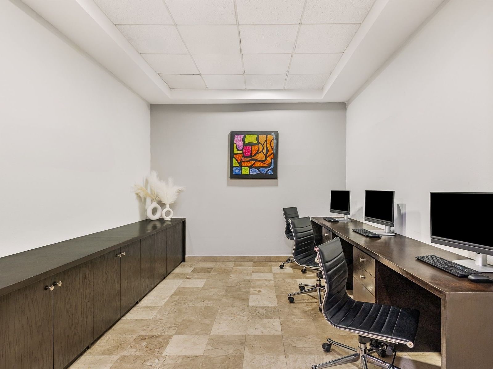 Centro de negocios en Fiesta Inn Express Nuevo Laredo con escritorio largo, computadoras y arte abstracto