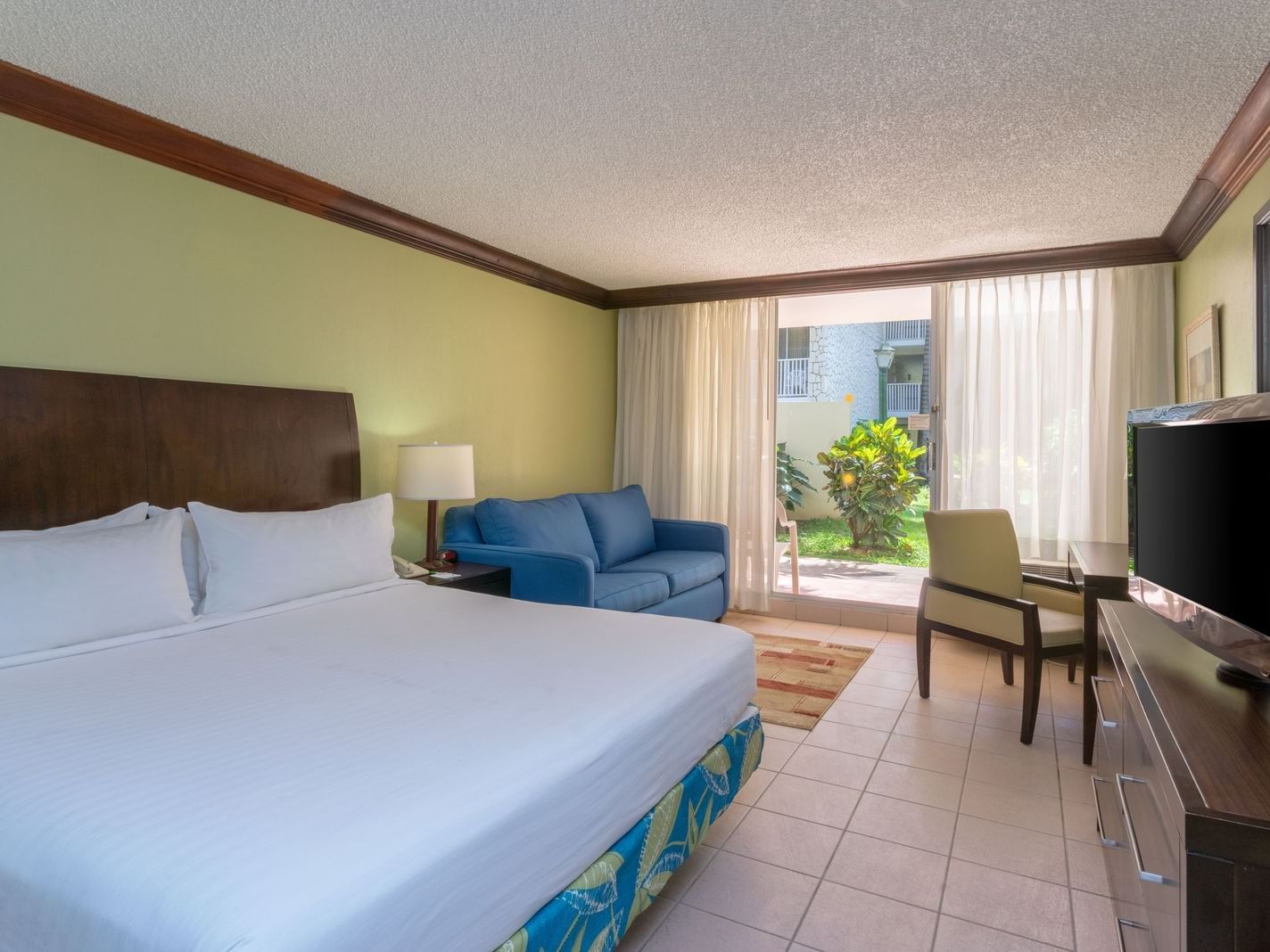Sofa by the king bed overlooking the patio lounge in Deluxe Room at Holiday Inn Montego Bay