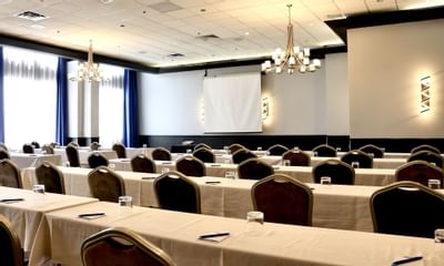 rangées de tables et de chaises face à un écran de projection